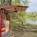 Felix sitzt vor unserem selbst ausgebauten VW T5 Bus Willi an einem See im Chiemgau